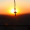 pexels-photo-2752462-2752462 A cross pendant hanging against a vibrant sunset sky, capturing a serene and spiritual moment.